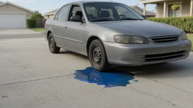 Small blue fluid puddle beneath the front of a parked car on a dry driveway