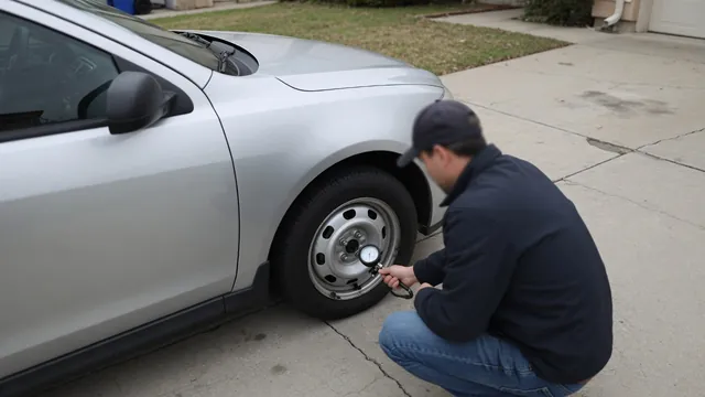 Driver checking tire pressure with a handheld gauge beside a parked car