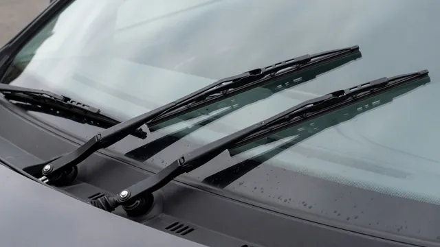 Windshield wiper arms resting at the base of a parked vehicle’s windshield