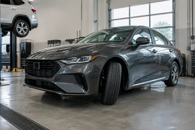 Parked car with a visible front strut and tire in a clean automotive service bay