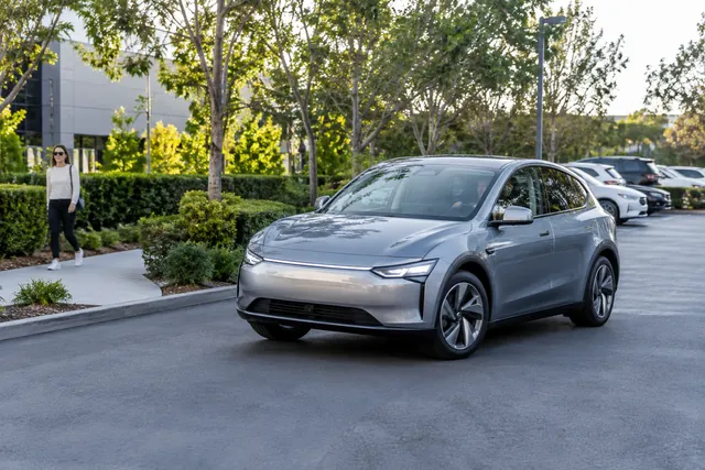 Electric car moving slowly through a parking area near a pedestrian walkway
