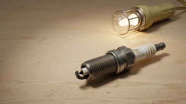 Spark plug with visible electrode wear resting on a workbench beside an inspection light
