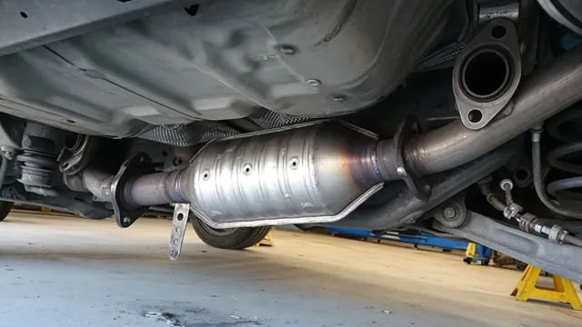 Catalytic converter and surrounding heat shield shown beneath a parked vehicle
