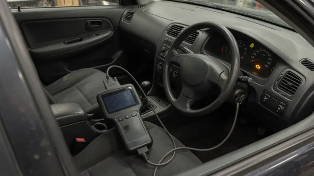 Diagnostic scan tool beside a vehicle dashboard with the check engine light illuminated