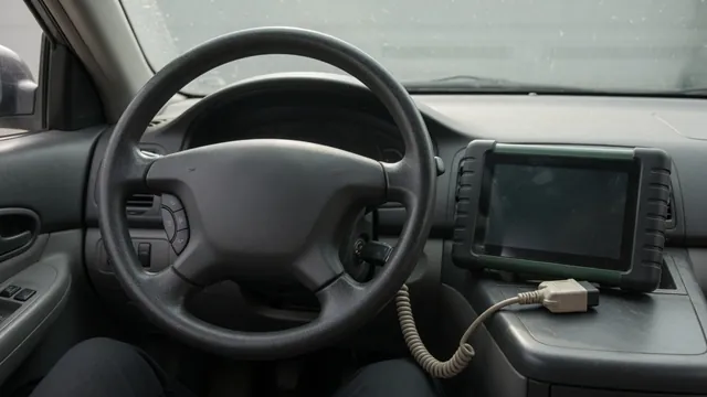 Cruise control buttons on a steering wheel beside a diagnostic scanner in a parked vehicle