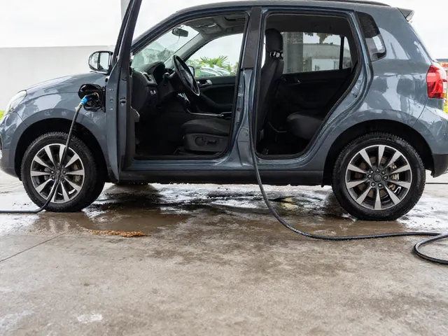 Ground-level rinse removing mud from a car’s lower underbody on a paved wash area