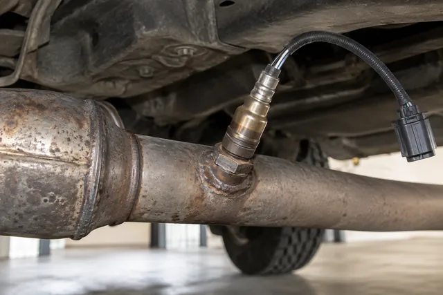 Illustration of an oxygen sensor threaded into a Jeep exhaust pipe with its wiring connector visible