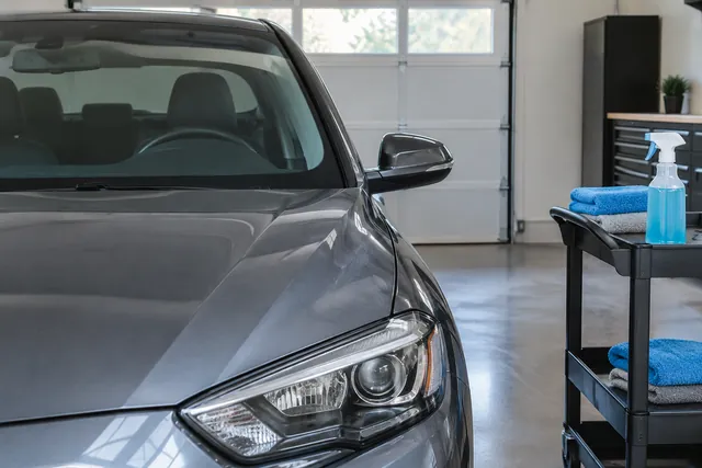 Car windshield and headlight beside glass cleaner, microfiber towels and surface care products