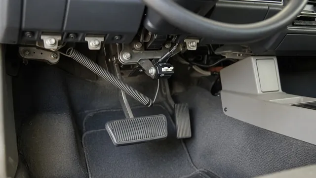 Driver footwell showing the brake pedal, pivot bracket, return spring, and nearby switch
