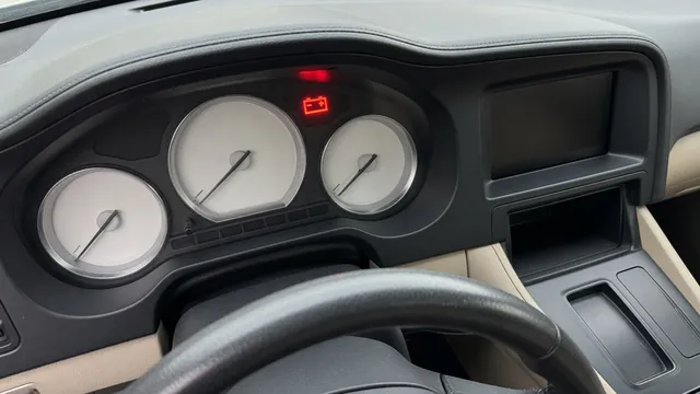 Battery-shaped charging system warning light illuminated on a car dashboard