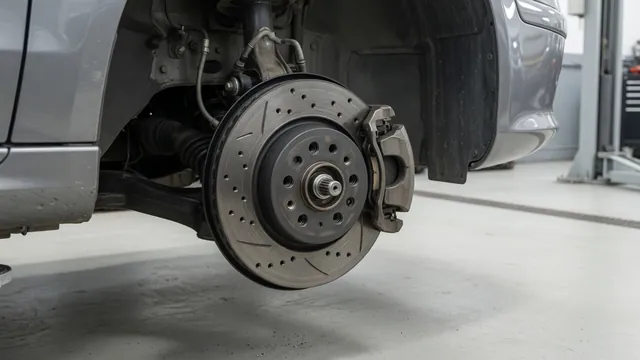Close-up of a brake rotor, pads, and caliper on a stationary vehicle in a service bay