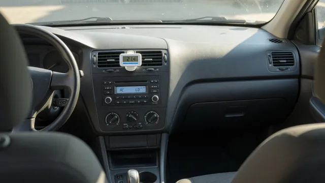 Car dashboard with AC cooling controls selected and a thermometer positioned at an air vent