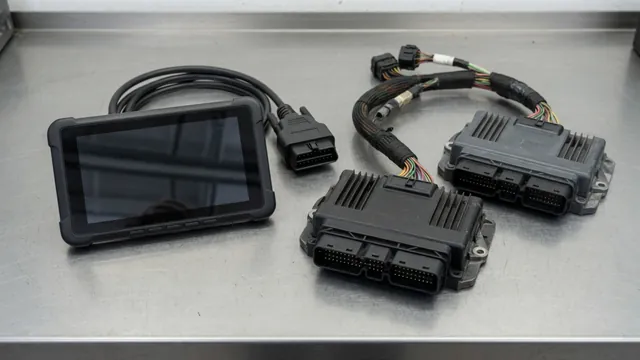 Diagnostic scanner beside transmission and engine control modules on an automotive workbench