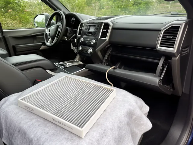 Ford cabin interior with an open glove box and a replacement cabin air filter nearby
