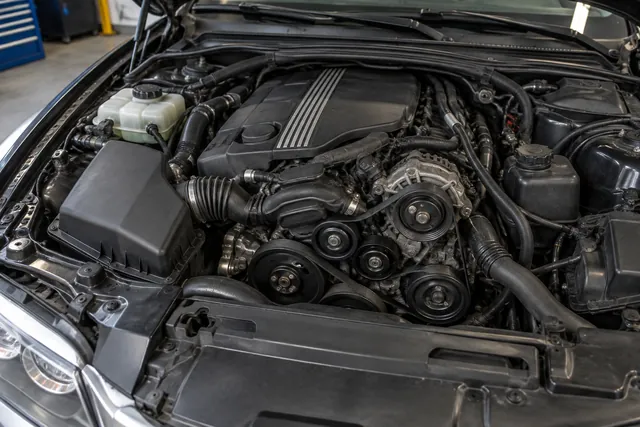BMW engine bay with the engine off and the serpentine belt and accessory pulleys visible