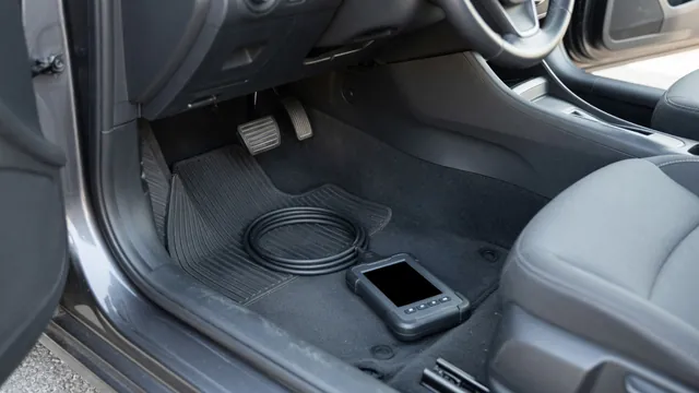 Driver footwell showing separate brake and accelerator pedals with an automotive scan tool nearby