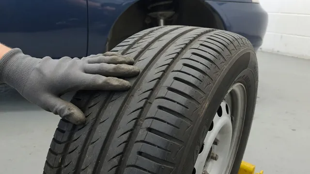 Gloved hand feeling feathered, uneven wear across the tread ribs of a car tire