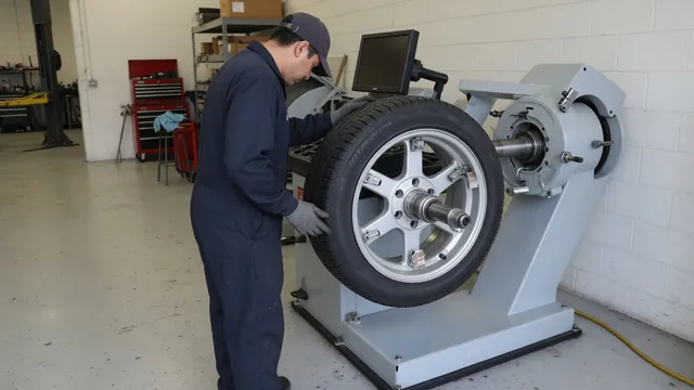 Technician inspecting a tire and wheel secured on a balancing machine in an automotive shop