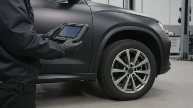 Technician checking tire sensor information on a scan tool beside a parked vehicle