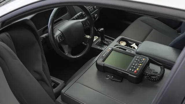 Diagnostic scanner beside a steering wheel with cruise control buttons in a parked vehicle