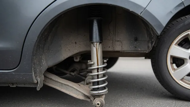 Shock absorber with an oily trail on its housing, visible inside a parked vehicle’s rear wheel well