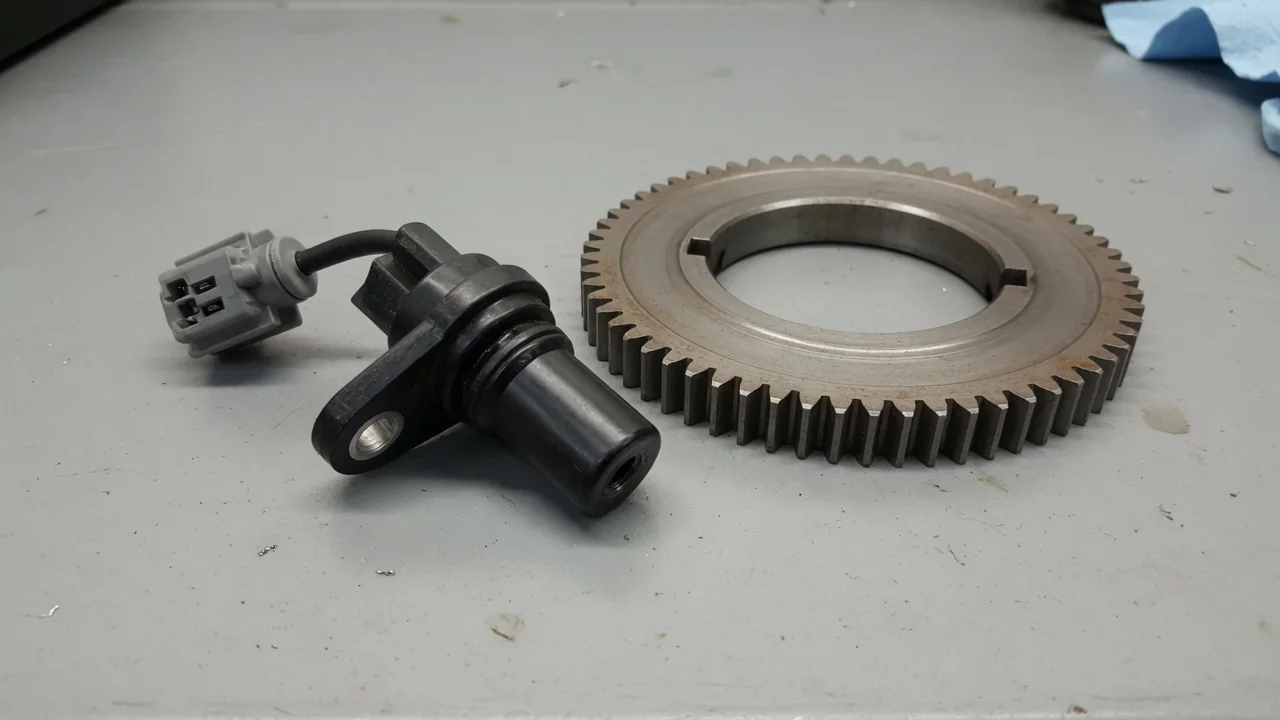Illustration of a crankshaft position sensor near a crankshaft reluctor wheel with an electrical connector
