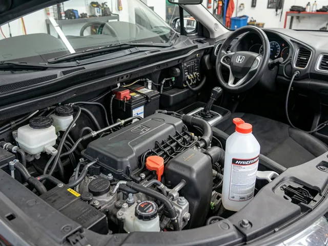 Brake fluid reservoir in a Honda engine bay with a sealed brake fluid bottle nearby