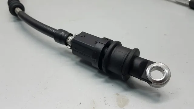 Automatic transmission shift cable with its end fitting and bushing shown on a workbench