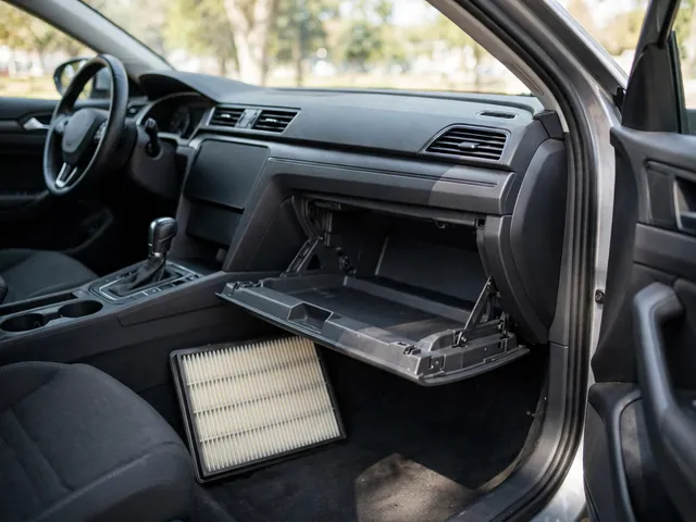 Cabin air filter beside an open glove compartment in a parked sedan