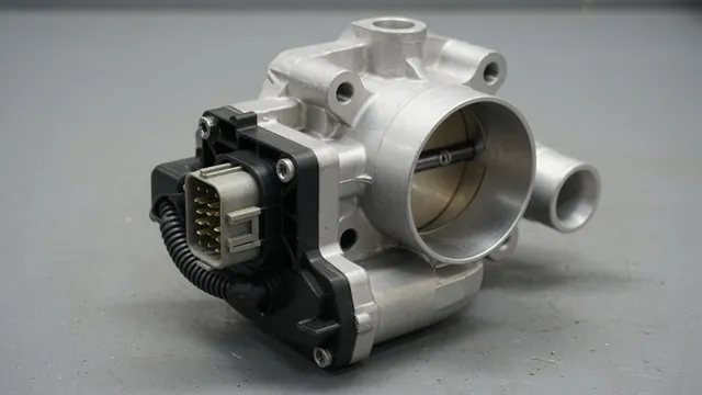 Electronic throttle body on a workbench with the throttle position sensor and its wiring connector mounted on the side of the housing