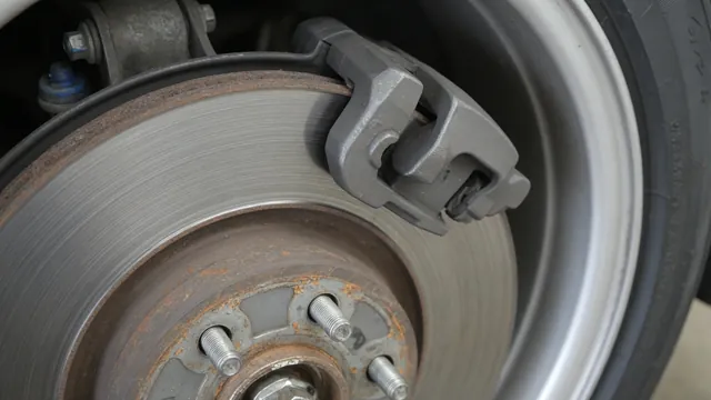 Brake rotor with visible surface rust and circular scoring beside a mounted brake caliper.