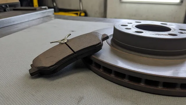 Brake pad with its metal wear-indicator tab visible beside a brake rotor
