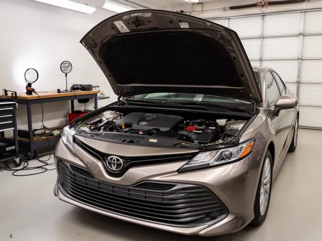 Toyota Camry engine bay with a flashlight and inspection mirror ready for a PCV valve location check
