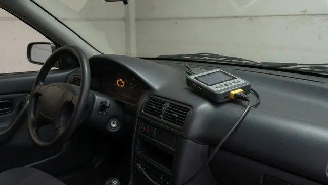 Handheld diagnostic scanner beside a car dashboard with an illuminated check engine light