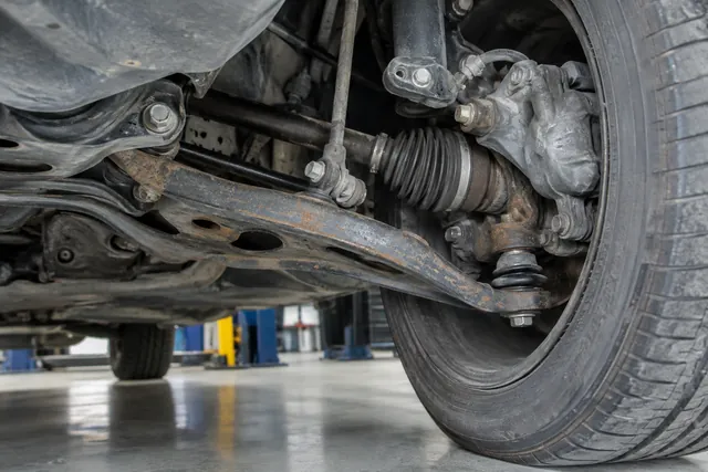 Clean suspension control arm, rubber bushing and ball joint visible inside a car wheel well