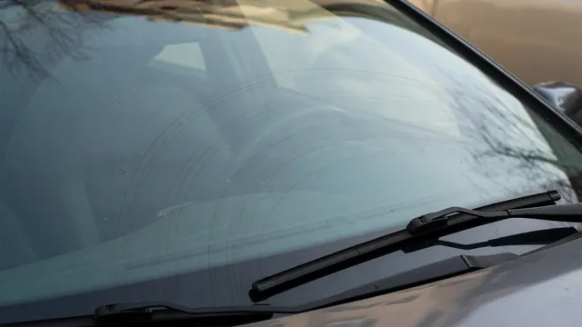 Curved wiper scratches visible on a windshield beside a resting wiper blade