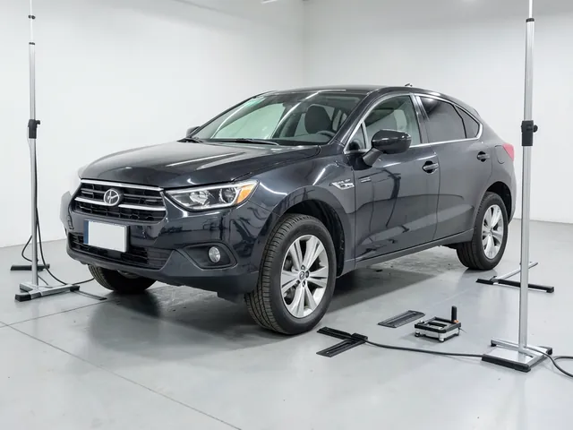 Car on a level garage floor with wheel alignment strings, toe plates and a camber gauge nearby.