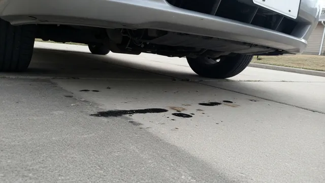 Small oil spots on a driveway beneath the front of a parked car