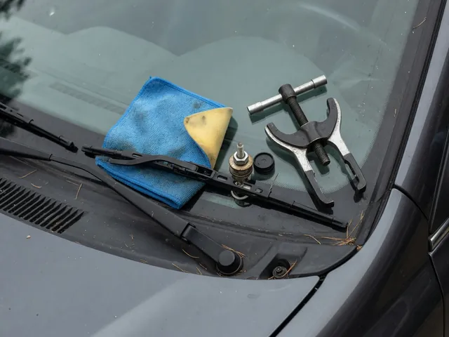 Windshield wiper arm mounting point with a dedicated puller tool beside the protected windshield