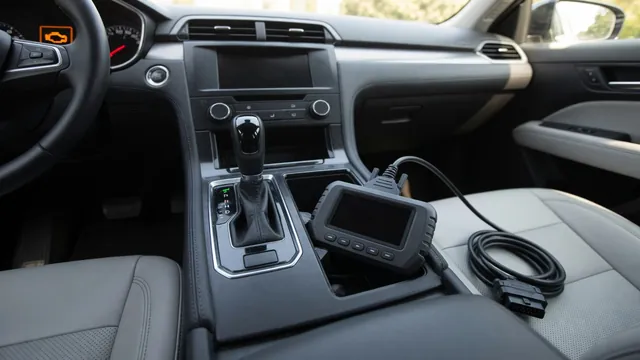 Car gear selector with an amber engine warning light on the dash and an OBD-II scan tool nearby