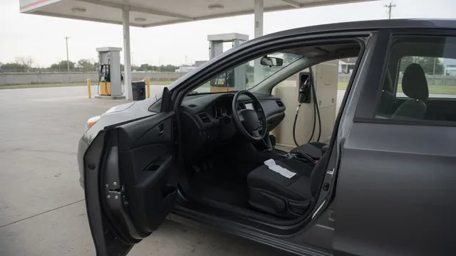 Parked car beside a fuel pump with its engine off and a fuel receipt on the center console
