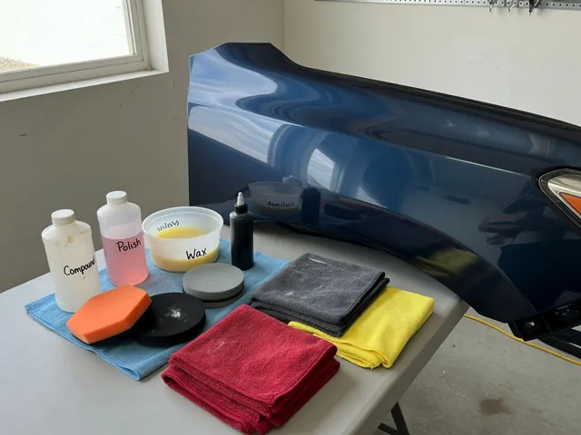 Car detailing supplies with wax, polish, sealant and compound beside a clean painted panel