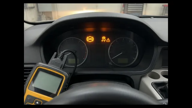 Dashboard with ABS and traction control warning lights on, and a diagnostic scan tool connected under the dash